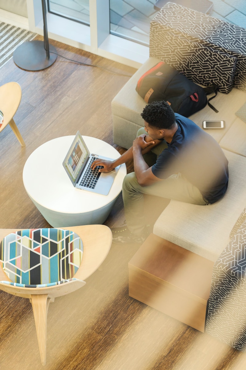 man sitting on couch using MacBook